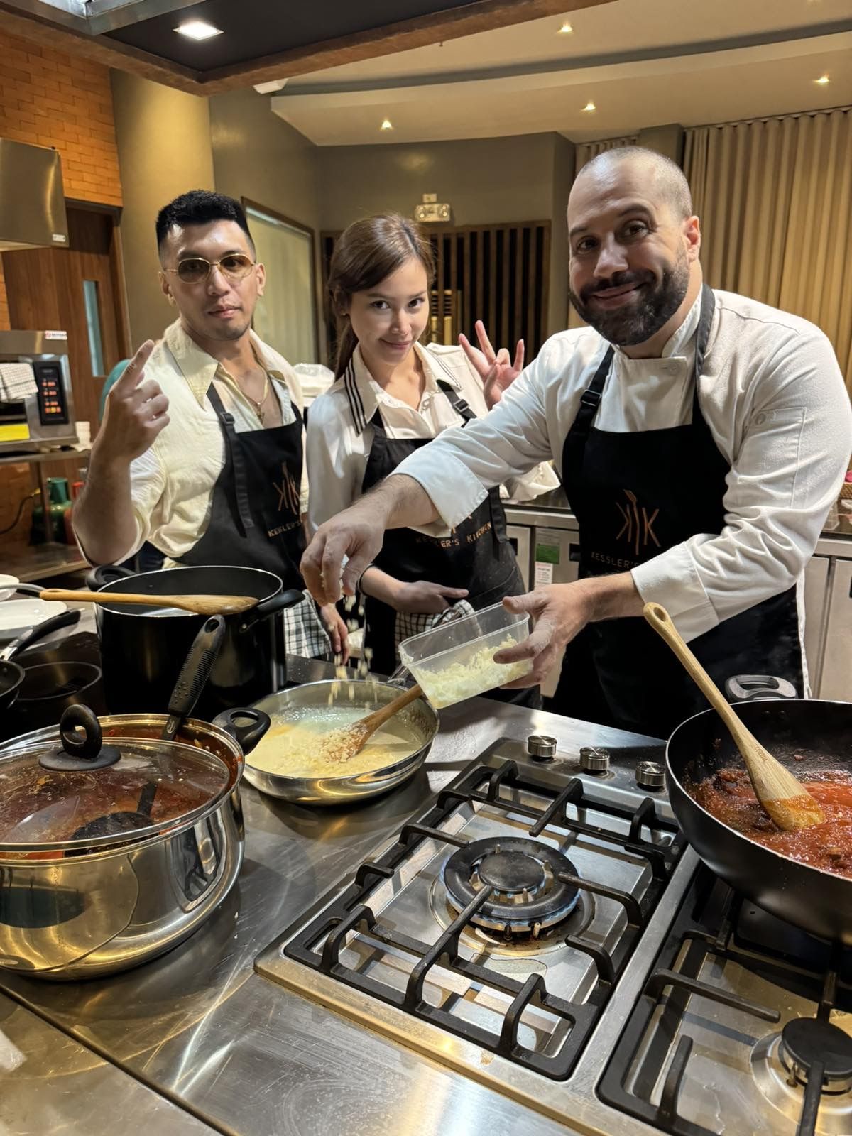Chef Moreno Benigno at the stove with film director Christian Paolo Lat and actress Apple Dy