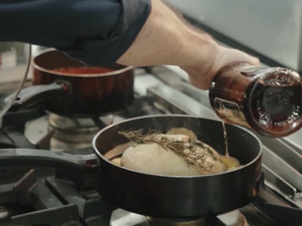 Chef Moreno pouring brandy over foie gras in the pan